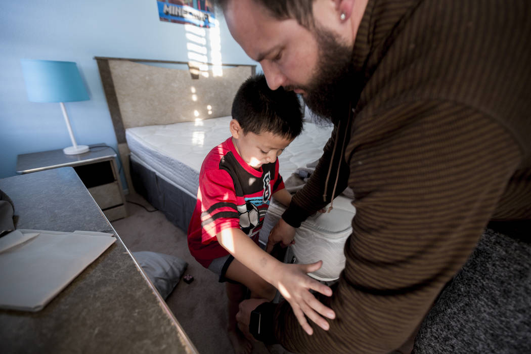 Maximus Calderon, 6, puts on pants with the help of his dad William King in their Las Vegas home Friday morning, Dec. 8, 2017, while they get ready for school. Elizabeth Brumley Las Vegas Review-J ...
