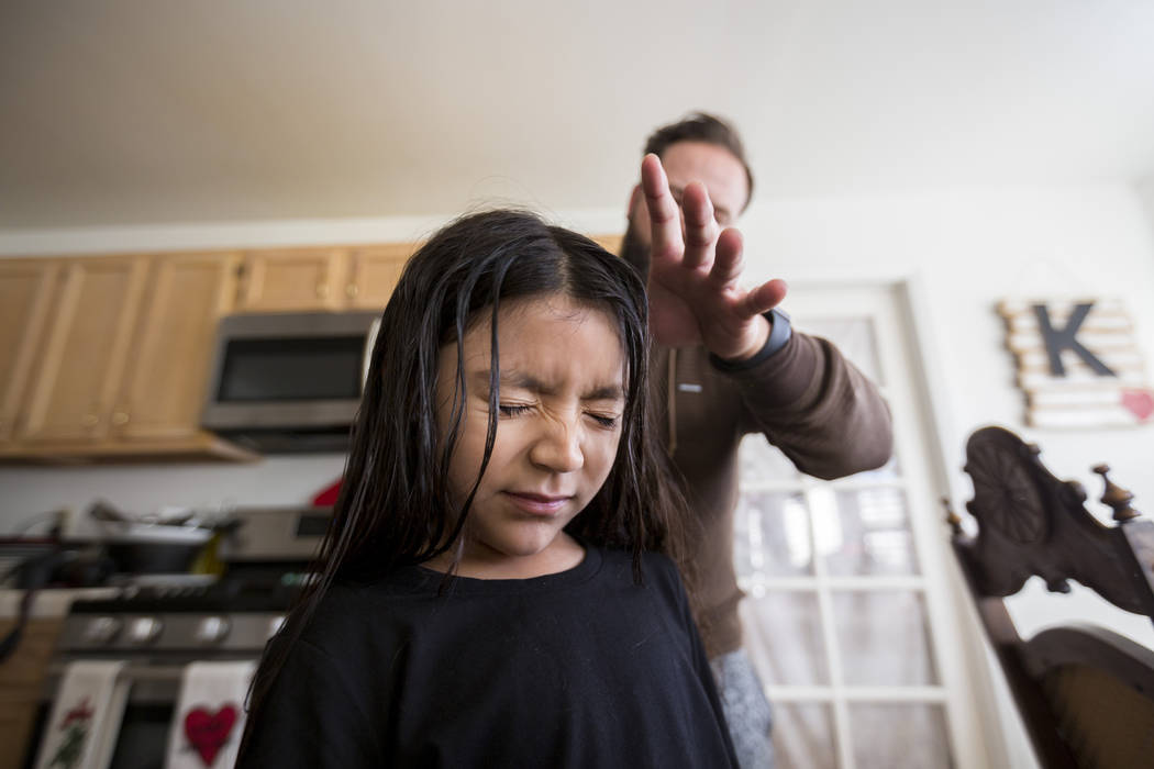 Velonee Calderon, 8, squints as her dad William King brushes her hair in their Las Vegas home as they get ready for school Friday, Dec. 8, 2017. Elizabeth Brumley Las Vegas Review-Journal  @EliPag ...