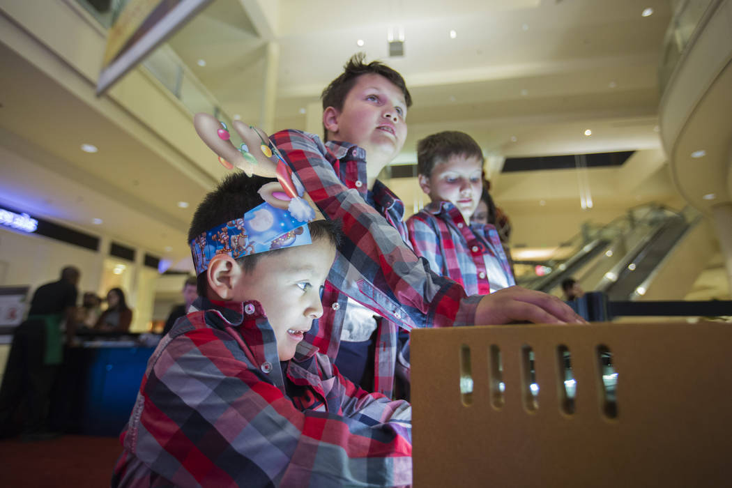 Maximus Calderon, 6, from left, Eli king, 8, Enoch King, 9, play the keyboard that makes the lights on the Christmas trees change with the note played at Fashion Show Mall in Las Vegas Wednesday,  ...
