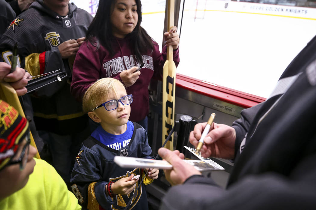 Las Vegas resident Gavin Trudell, 8, looks up at Golden Knights goalie Marc-Andre Fleury as he gets an autograph on his hockey stick following the NHL team's practice at the City National Arena in ...