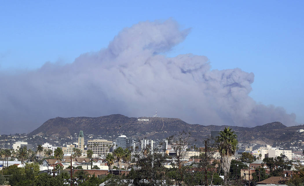 Smoke from the Creek wildfire in the San Gabriel Mountains, the second range behind the Hollywood Hills, home of the Hollywood sign, looms up over Los Angeles Tuesday morning, Dec. 5, 2017 (AP Pho ...