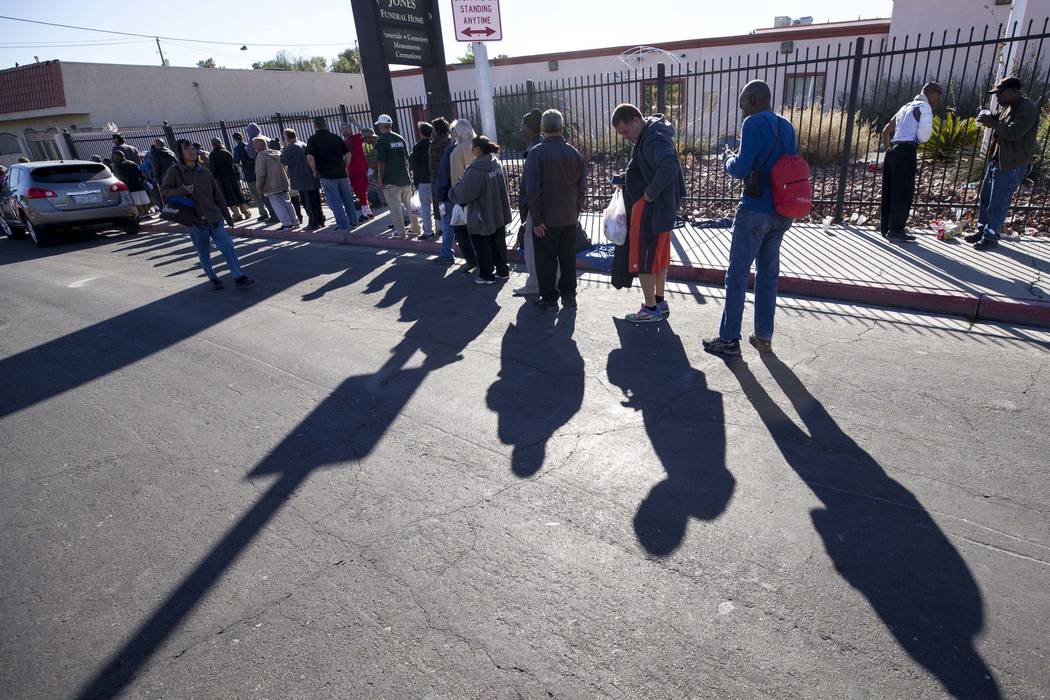 A line homeless people wait for food handouts on Foremaster Lane between Las Vegas Blvd. and Ma ...