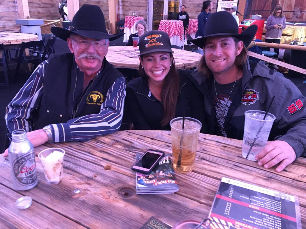From left, Randy Denning, Tiffany Chavez and Kobi Works, all in town from Comanche, Texas, settle in to good seats at a big table for the Wrangler NFR viewing party at the Downtown Las Vegas Event ...