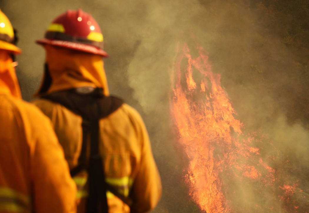 In this photo provided by the Santa Barbara County Fire Department, firefighters keep an eye on flames as pockets of unburned vegetation flare up off Bella Vista Dr. in Montecito, Calif., Wednesda ...