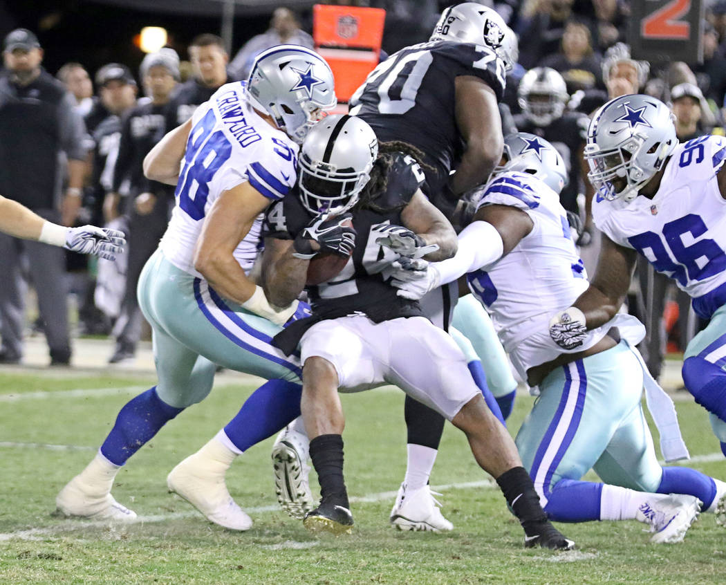 Oakland Raiders running back Marshawn Lynch (24) is tackled by Dallas Cowboys wide receiver Dez Bryant (88) during the first half of a NFL game in Oakland, Calif., Sunday, Dec. 17, 2017. Heidi Fan ...