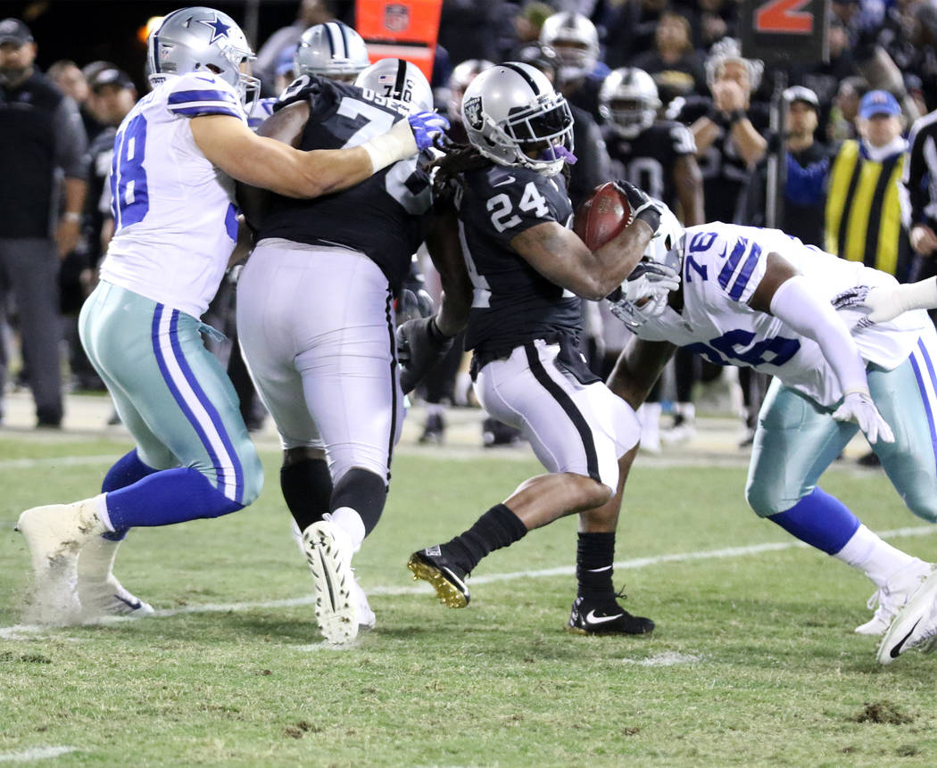 Oakland Raiders running back Marshawn Lynch (24) runs with the football as Dallas Cowboys nose tackle Richard Ash (76) comes in to tackle him during the first half of a NFL game in Oakland, Calif. ...