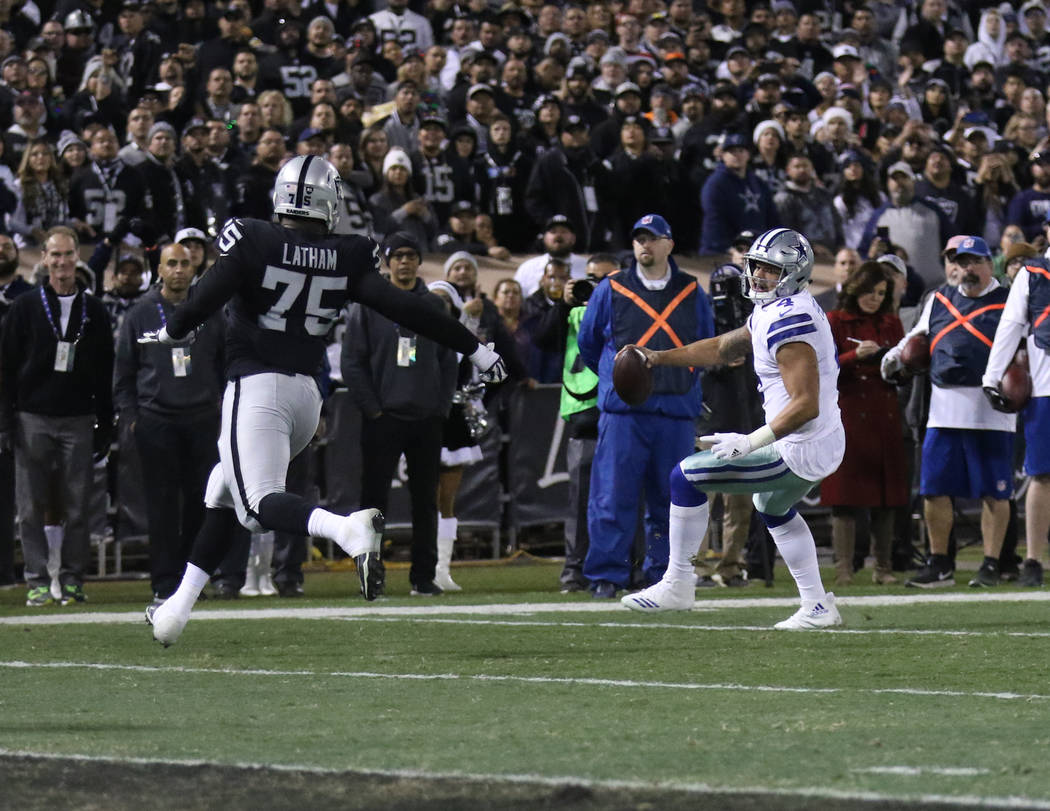 Dallas Cowboys quarterback Dak Prescott (4) rushes toward the end zone during the first half of a NFL game as Oakland Raiders defensive tackle Darius Latham (75) closes in in Oakland, Calif., Sund ...