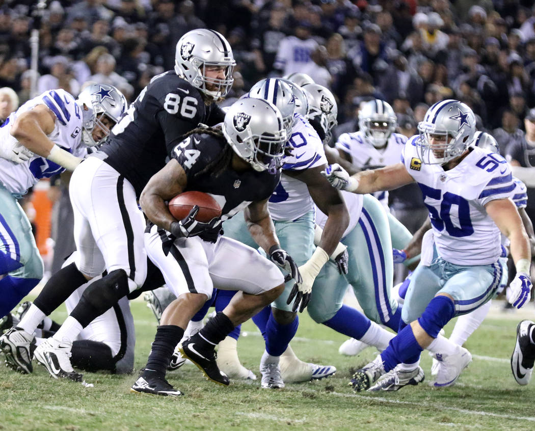 Oakland Raiders running back Marshawn Lynch (24) carries the football as Dallas Cowboys middle linebacker Sean Lee (50) closes in on him during the first half of a NFL game in Oakland, Calif., Sun ...