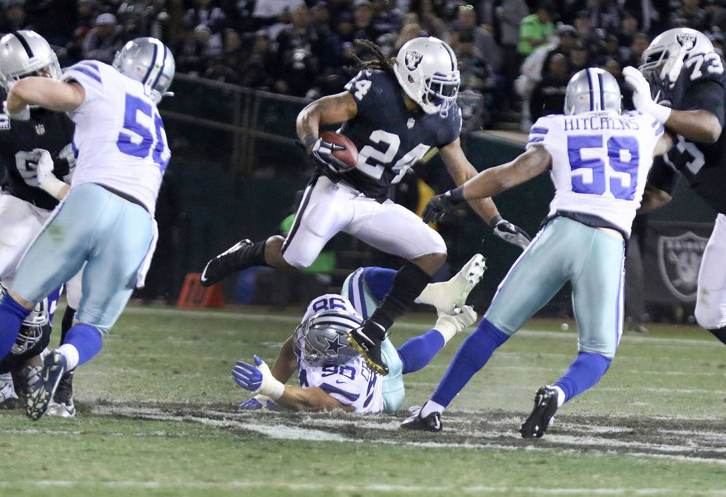 Oakland Raiders running back Marshawn Lynch (24) hurdles over Dallas Cowboys defensive end Tyrone Crawford (98) as he runs with the football during the first half of a NFL game in Oakland, Calif., ...