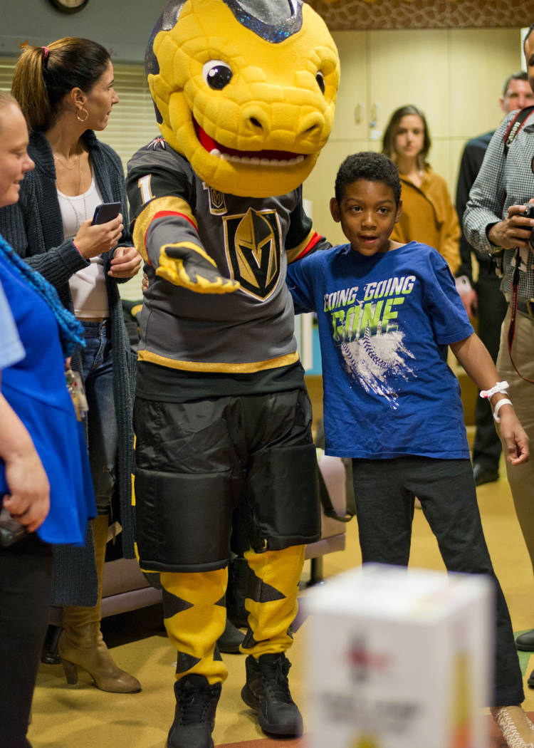 Vegas Golden Knights mascot Chance the Gila Monster shows Deangylo Pollard to a pile of presents during an event at the Children's Hospital of Nevada at University Medical Center in Las Vegas on T ...