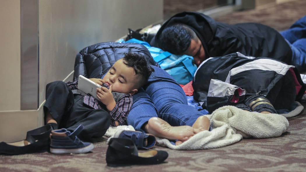 Kenneth Reyes, 2, watches phone cartoons as his parents, Lucas and Areli and sister, Yosselyn-11 sleep on the second floor of the atrium overnight into Monday morning, Dec. 18, 2017, at the airpor ...