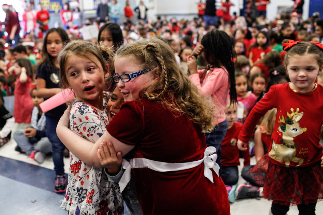 Kindergarten students Soleil Skalski, 5, left, Izabella Mendoza, 5, center, and Addison Wolf, 5, right, hug each other as donated gifts from Bob and Sandy Ellis are revealed at C. T. Sewell Elemen ...
