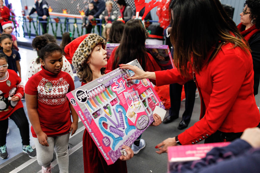 UNLV Athletic Director Desiree Reed-Francois hands out gifts donated by Bob and Sandy Ellis to students at C. T. Sewell Elementary School in Henderson, Friday, Dec. 22, 2017. This is the 13th year ...