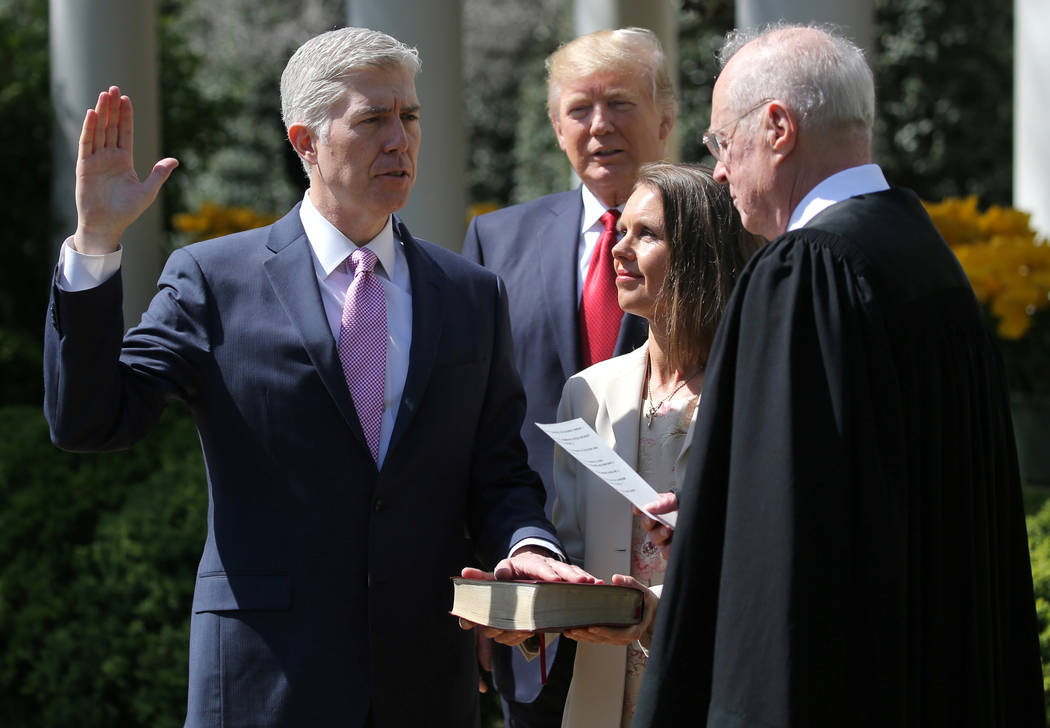 FILE PHOTO: Judge Neil Gorsuch (L) is sworn in as an associate justice of the Supreme Court by Supreme Court Associate Justice Anthony Kennedy (R) , as U.S. President Donald J. Trump (C) watches w ...