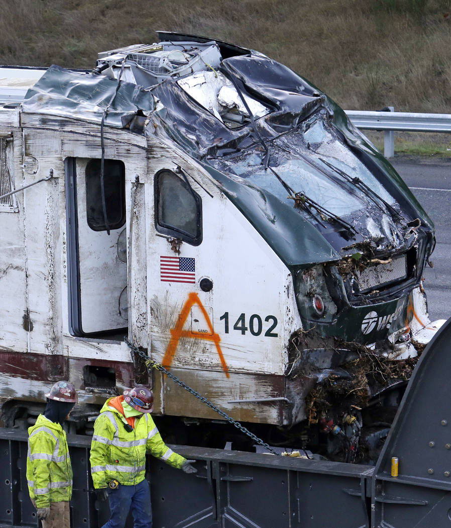 The engine from an Amtrak train crash onto Interstate 5 two days earlier is checked by workers before being transported away from the scene, Wednesday, Dec. 20, 2017, in DuPont, Wash. (AP Photo/El ...