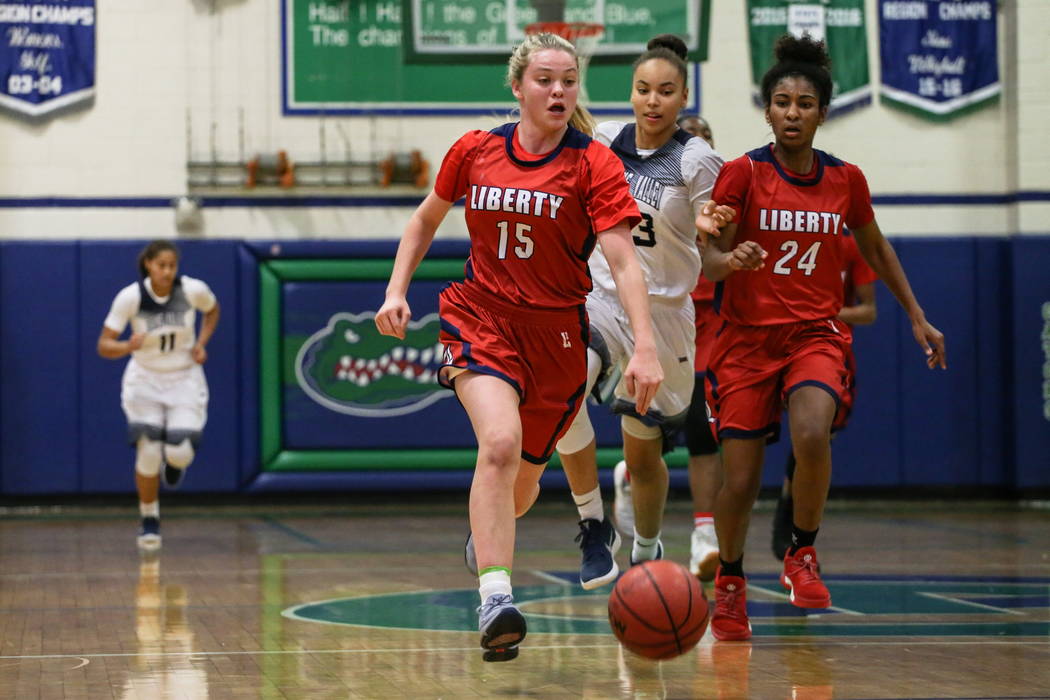 Liberty's London Pavlica (15) dribbles the ball past Spring Valley’s Alexus Quaadman (23) and Liberty's Trinity Vasquez (24) during the second quarter of the championship basketball game of ...