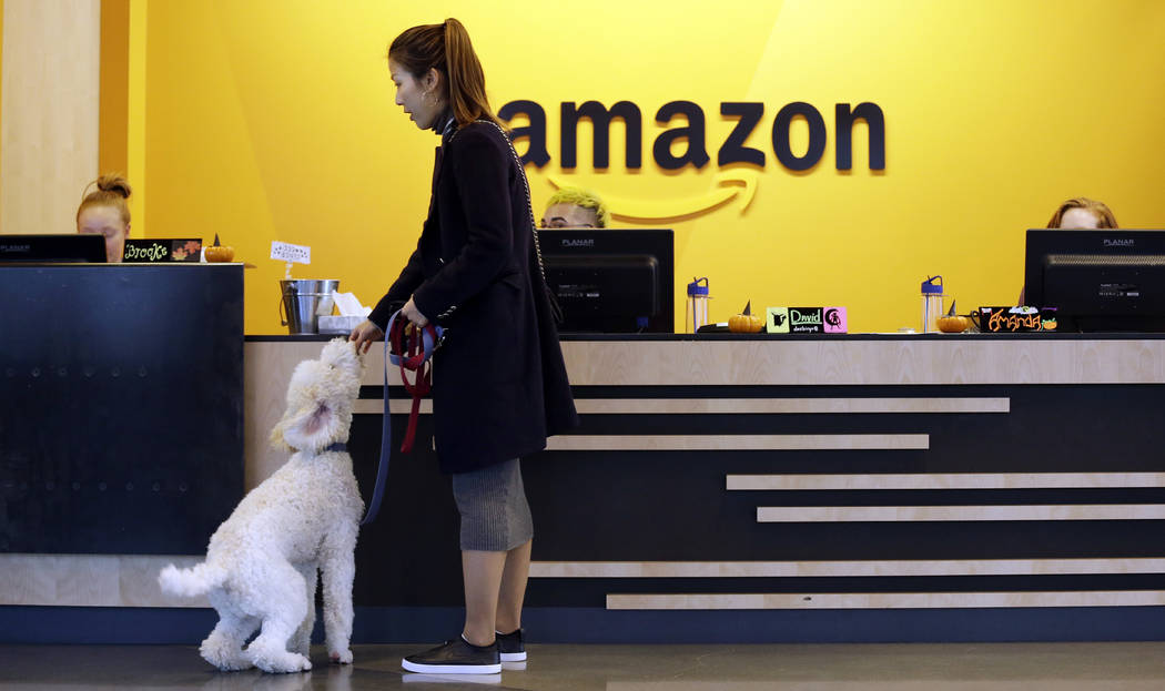 In this Wednesday, Oct. 11, 2017, photo, an Amazon employee gives her dog a biscuit as the pair head into a company building, where dogs are welcome, in Seattle. Whichever city lands Amazon&#x2019 ...