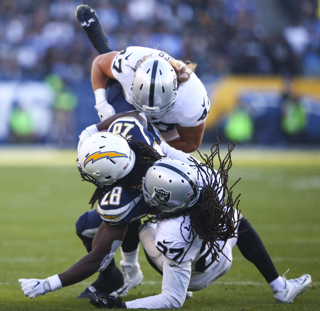 Los Angeles Chargers running back Melvin Gordon (28) gets tackled by Oakland Raiders defensive end James Cowser (47) and Oakland Raiders free safety Reggie Nelson (27) during an NFL game at StubHu ...