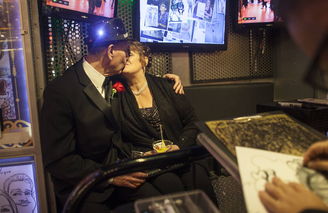 Duke Gressett and his wife Melody Gressett kiss as they have their caricature drawn at the Fremont Street Experience in Las Vegas, Sunday, Dec. 31, 2017, shortly after getting married. Rachel Asto ...