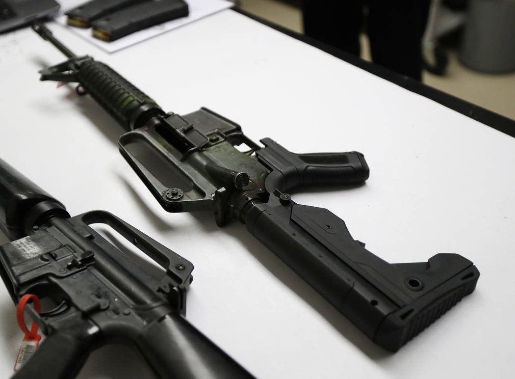 A semi-automatic rifle at right that has been fitted with a so-called bump stock device to make it fire faster sits on a table at the Washington State Patrol crime laboratory in Seattle on Jan. 11 ...