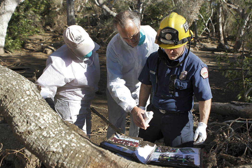 Paige Beard, from left, Curtis Skene and Montecito Fire Paramedic Kurt Hickman, try to identify a photo album found in the debris near East Valley Road in Montecito, Calif., Thursday, Jan. 25, 201 ...