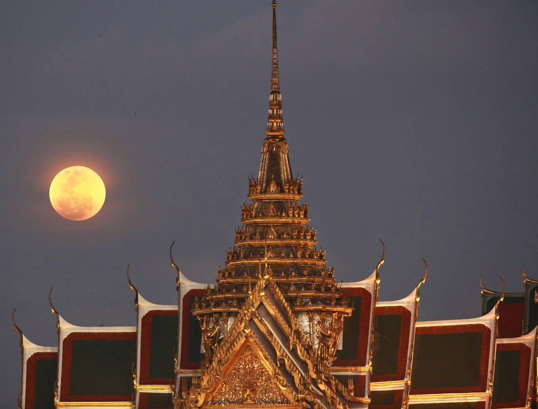 A full moon rises beside the Grand Palace in Bangkok, Thailand , Wednesday, Jan. 31, 2018. The moon is putting on a rare cosmic show. It's the first time in 35 years a blue moon has synced up with ...