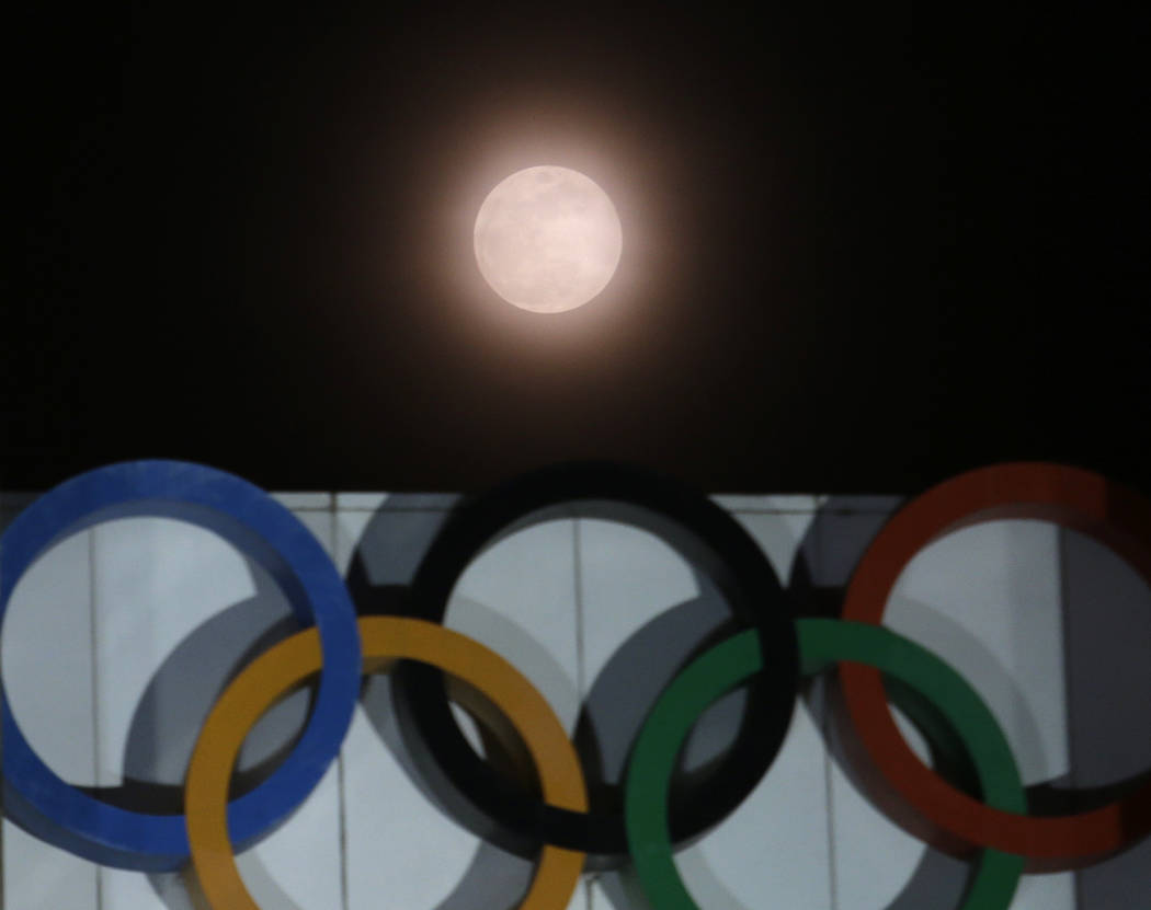 The full moon is seen over the Olympic rings on display at the Peace Gate at the Olympic Park in Seoul, South Korea, Wednesday, Jan. 31, 2018. The moon is putting on a rare cosmic show. It's the f ...