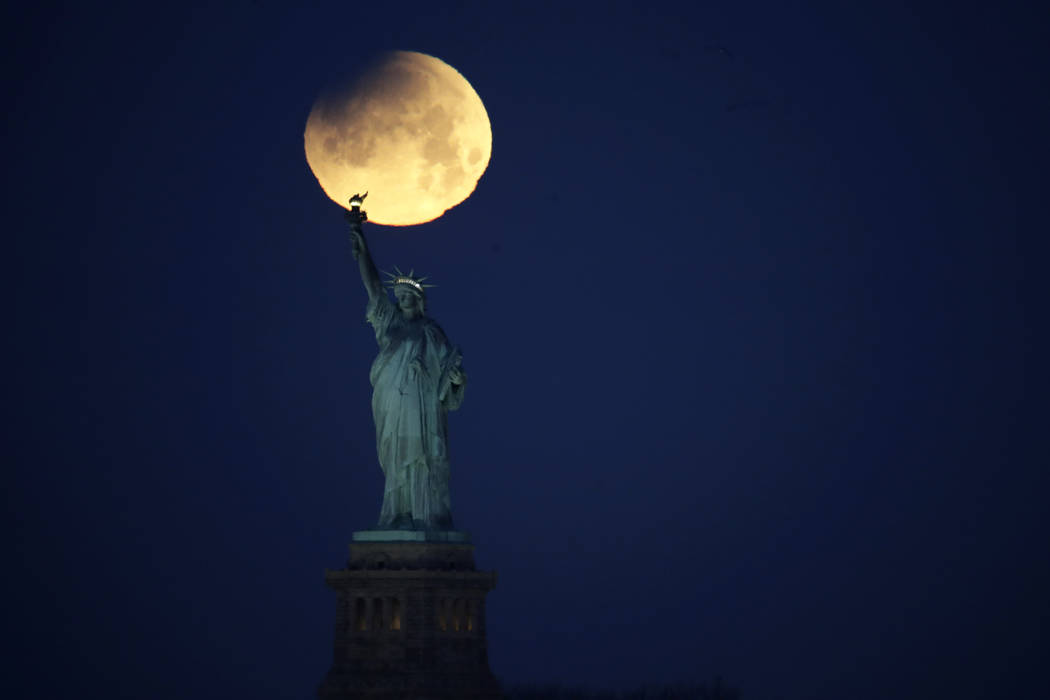 The Statue of Liberty is backdropped by a supermoon, Wednesday, Jan. 31, 2018, seen from the Brooklyn borough of New York. The supermoon, which is the final of three consecutive supermoons, also e ...