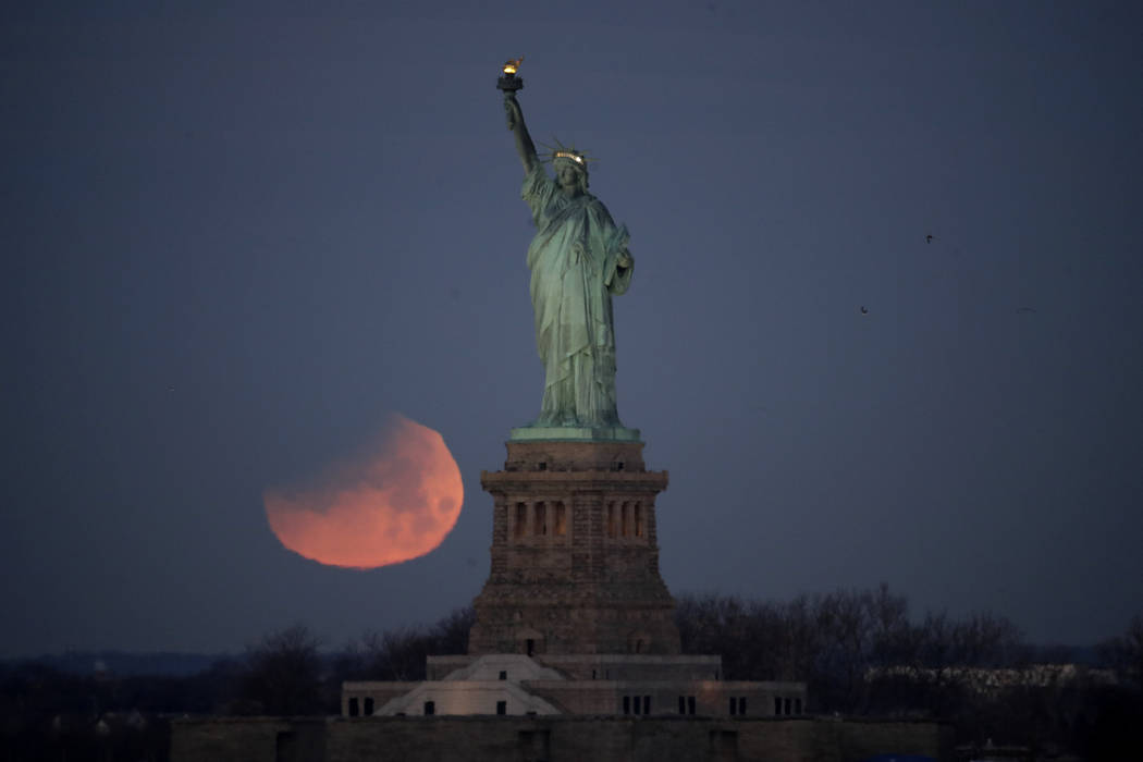 The Statue of Liberty is backdropped by a supermoon, Wednesday, Jan. 31, 2018, seen from the Brooklyn borough of New York. The supermoon, which is the final of three consecutive supermoons, also e ...