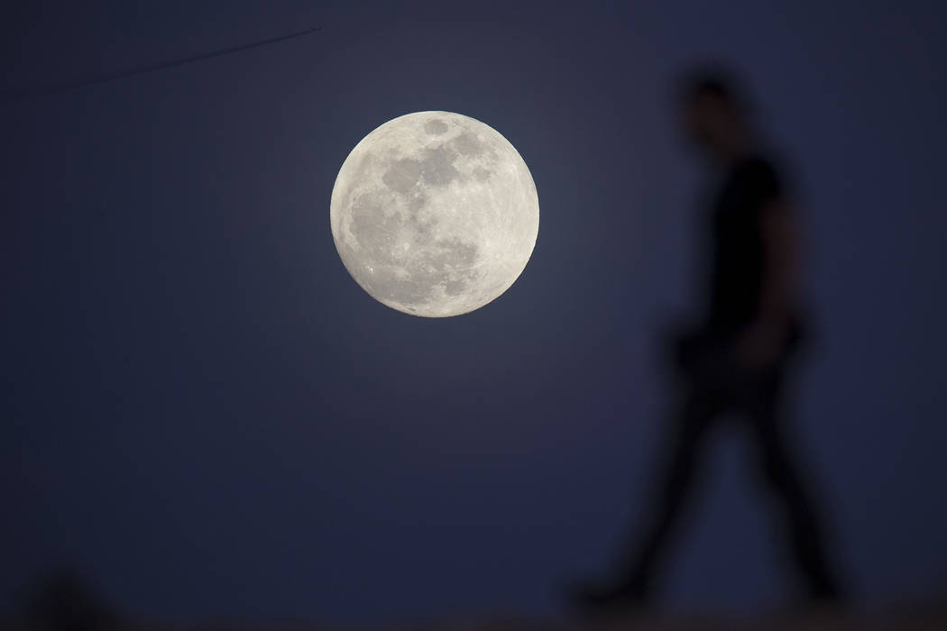 Ultimate Fighter Championship videographer Chris Warner walks past the moon as he films b-roll in Las Vegas on Tuesday, Jan 30, 2018. (Richard Brian/Las Vegas Review-Journal via AP)