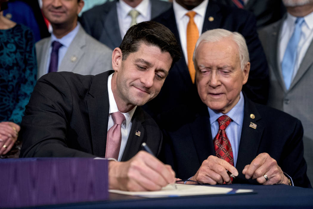 Speaker of the House Paul Ryan, R-Wis., left, accompanied by Senate Finance Committee Chairman Orrin Hatch, R-Utah, signs the final version of the GOP tax bill during an enrollment ceremony at the ...