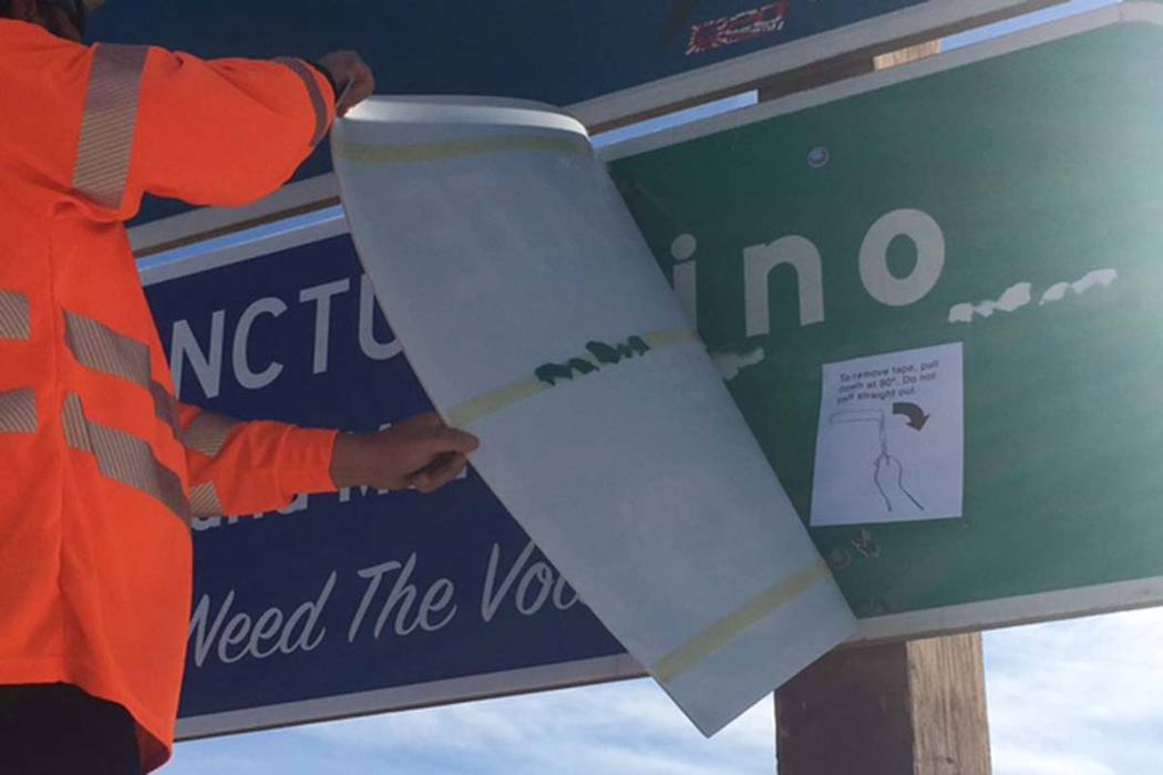 A California Department of Transportation worker removes a "sanctuary state" sign Monday from the San Bernardino county line on Interstate 15 near the California-Nevada border. (Courtesy of Califo ...