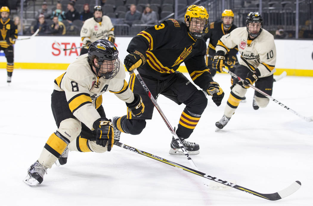 Michigan Tech Huskies forward Dylan Steman (8) and Arizona State Sun Devils defenseman Gvido Jansons (3) chase the puck during the inaugural Ice Vegas Invitational college hockey tournament at T-M ...