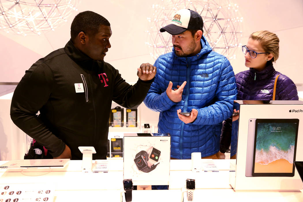 T-Mobile Signature Mobile Expert Byron Stewart, left, helps Raneto Watanabe, center, and Andreya Furreil of Brazil on opening night of the nightclub-themed signature store on the Strip Thursday, J ...