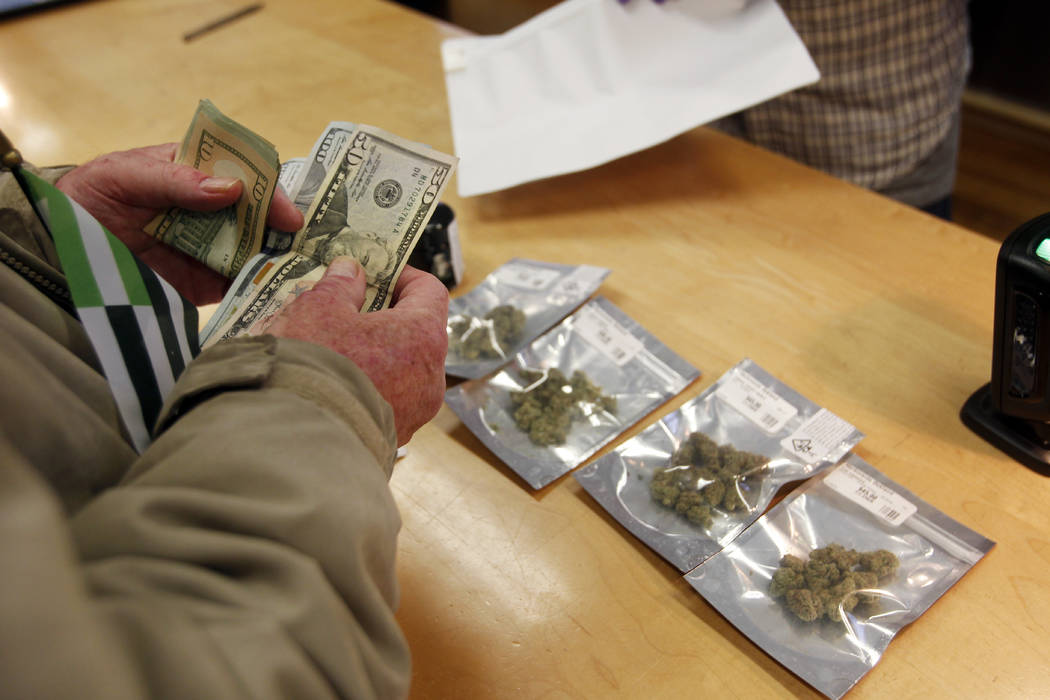 A customer purchases marijuana at Harborside marijuana dispensary, Monday, Jan. 1, 2018, in Oakland, Calif. Starting New Year's Day, recreational marijuana can be sold legally in California. (Math ...