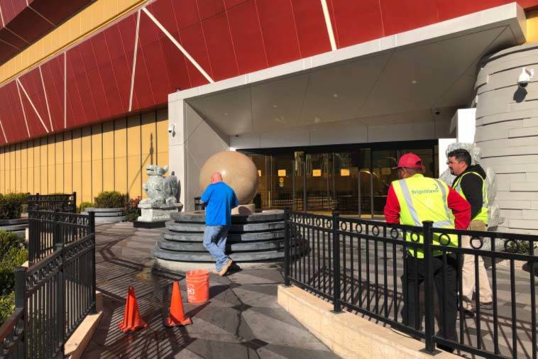Construction workers turn off the water-spinning stone ball outside the Lucky Dragon Thursday morning, Jan. 4, 2018. The hotel-casino posted signs saying the casino has been closed. The hotel rema ...
