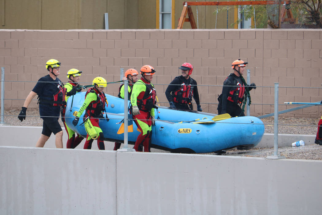 A rescue crew carries away a boat used to rescue a man and a woman under a bridge along the Las Vegas Wash, on east Carey Avenue near Pecos Road,  on Tuesday, Jan. 9, 2018. (Greg Haas/Las Vegas Re ...