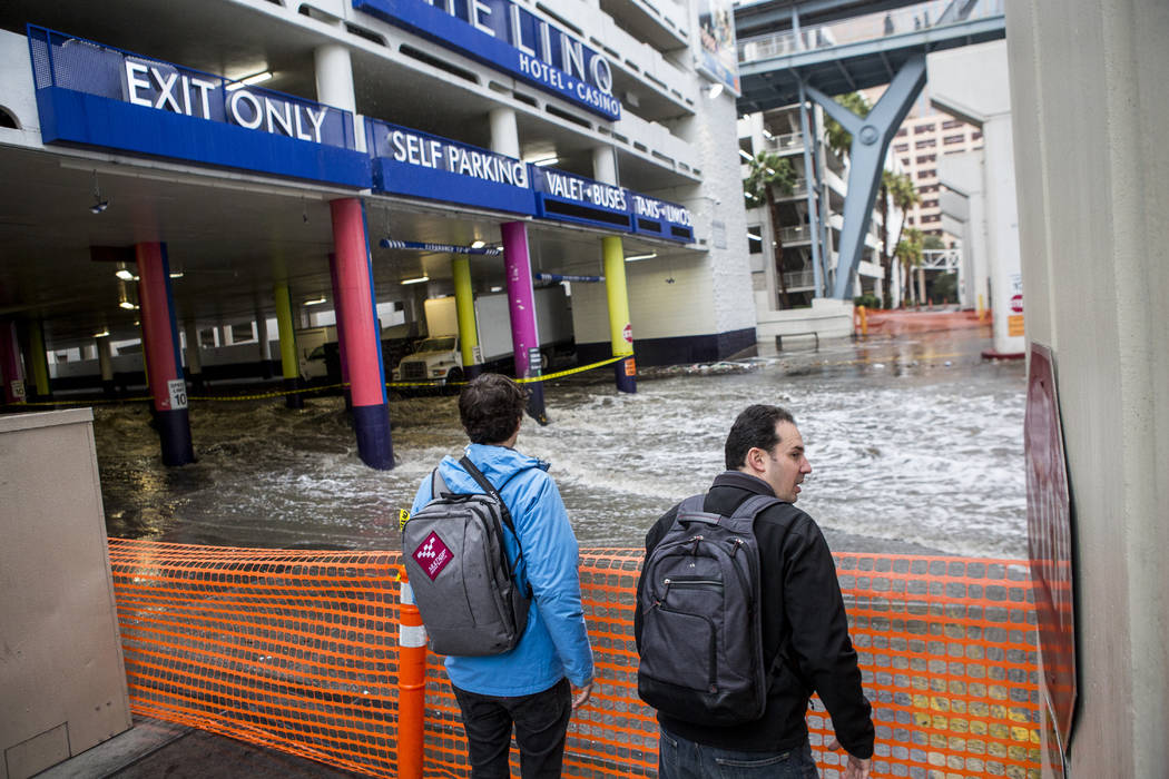 Jon, left, and Ben Gaiser, who are both attending CES, watch flood waters rush by The Linq Hotel in Las Vegas on Tuesday, Jan. 9, 2018. Patrick Connolly Las Vegas Review-Journal @PConnPie