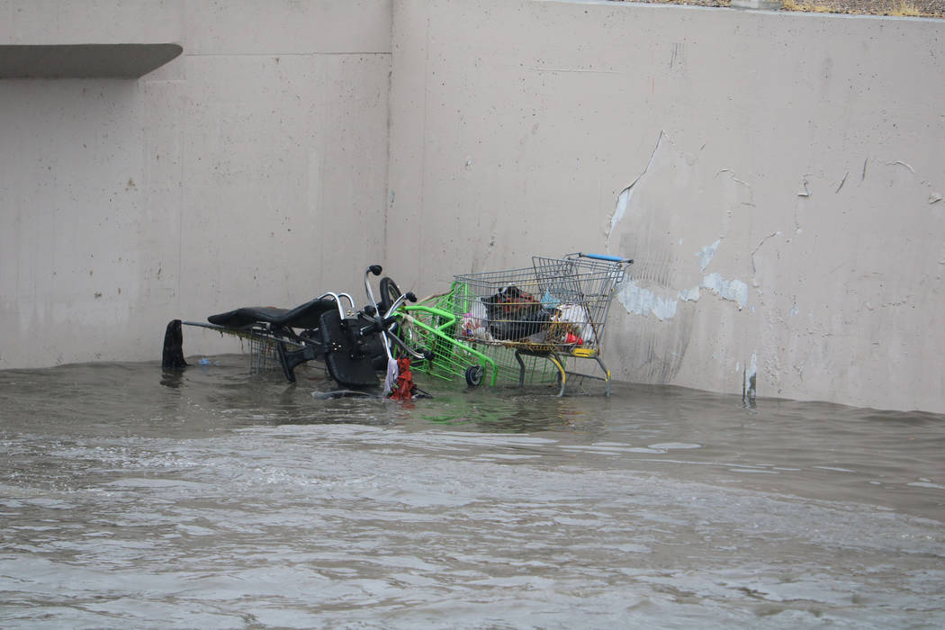 Shopping carts are half-submerged in floodwaters about 100 yards below the site where crews rescued a man and a woman under a bridge on east Carey Avenue along the Las Vegas Wash on Tuesday, Jan.  ...