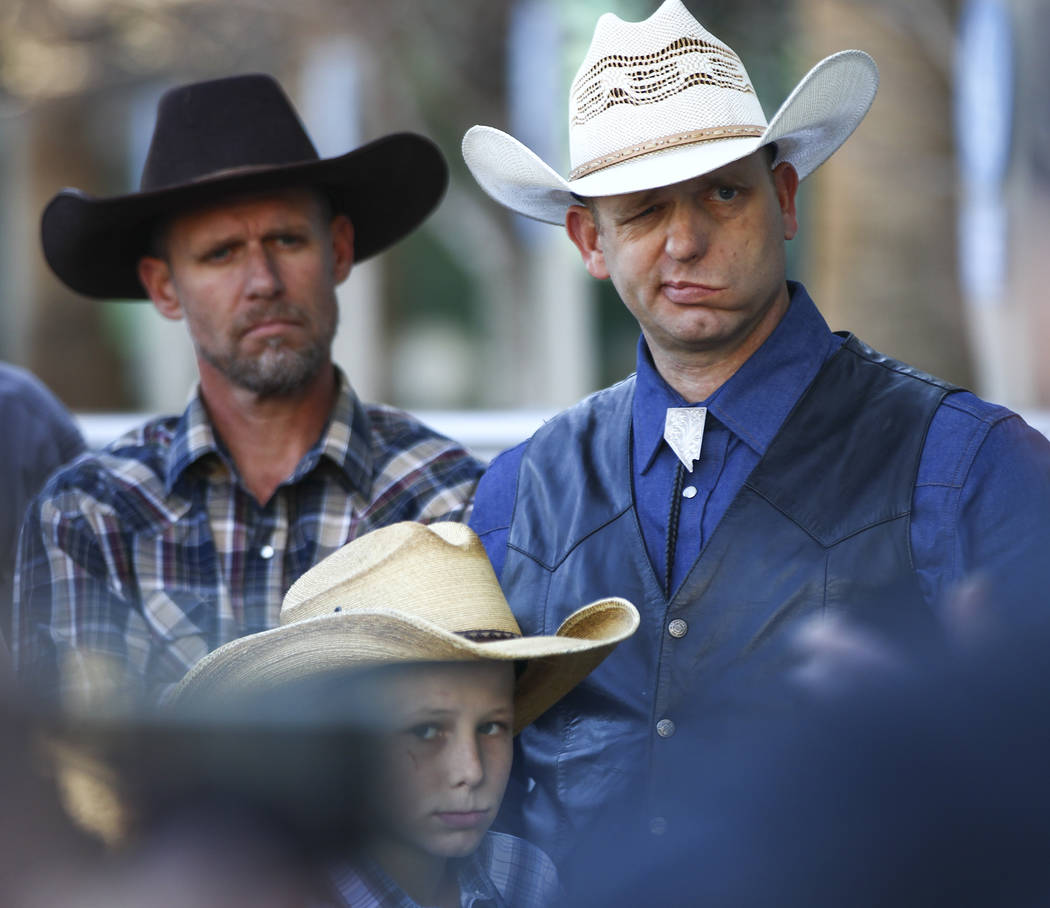 Ryan Bundy, son of rancher Cliven Bundy, right, listens to his father speak at Las Vegas Metropolitan Police Department headquarters two days after federal charges were dismissed against both of t ...
