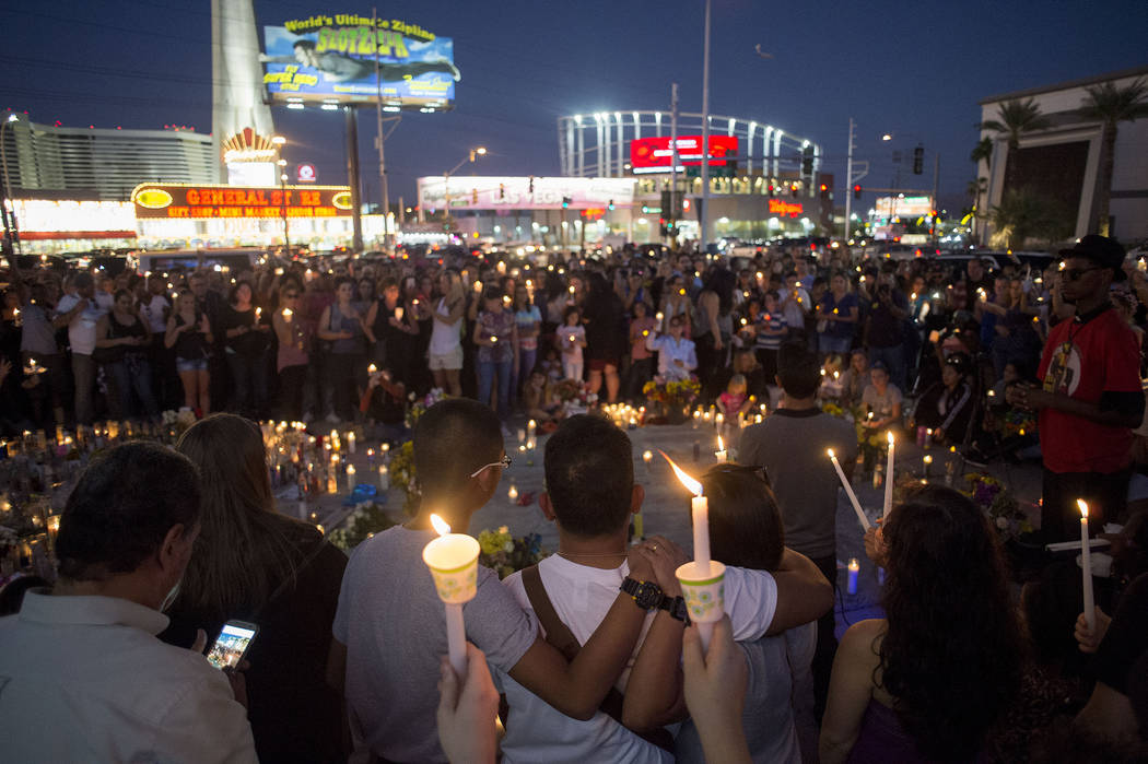 Attendees raise candles during a vigil in honor of the victims exactly one week after the mass shooting on Oct. 1, 2017, on the corner of Sahara Avenue and Las Vegas Boulevard in Las Vegas, Sunday ...