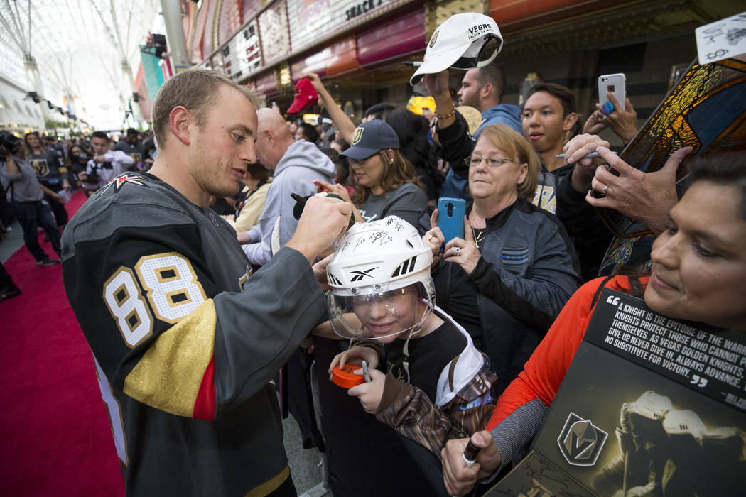 Vegas Golden Knights defenseman Nate Schmidt (88) autographs the helmet of Las Vegas resident Hunter Klingenneier, 12, during the team's first fan fest at the Fremont Street Experience in downtown ...