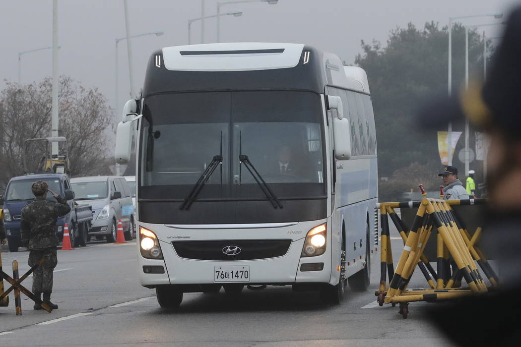 A South Korean soldier, left, salutes as a bus carrying the South Korean delegations passes at Unification Bridge, which leads to the Panmunjom in the Demilitarized Zone in Paju, South Korea, Mond ...