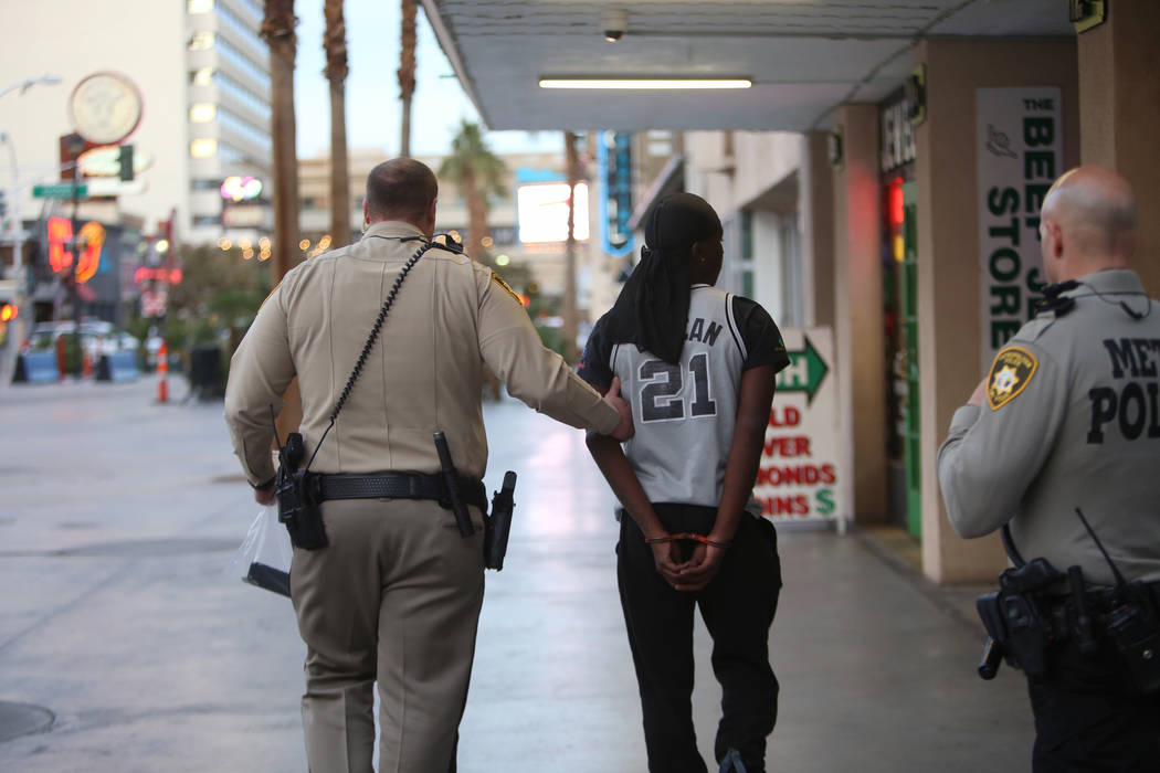 A Metro officer walks away an arrested individual near the Fremont Street Experience in Las Vegas, Monday, Jan. 15, 2018. A large fight occurred nearby with around 100 people involved and eight we ...