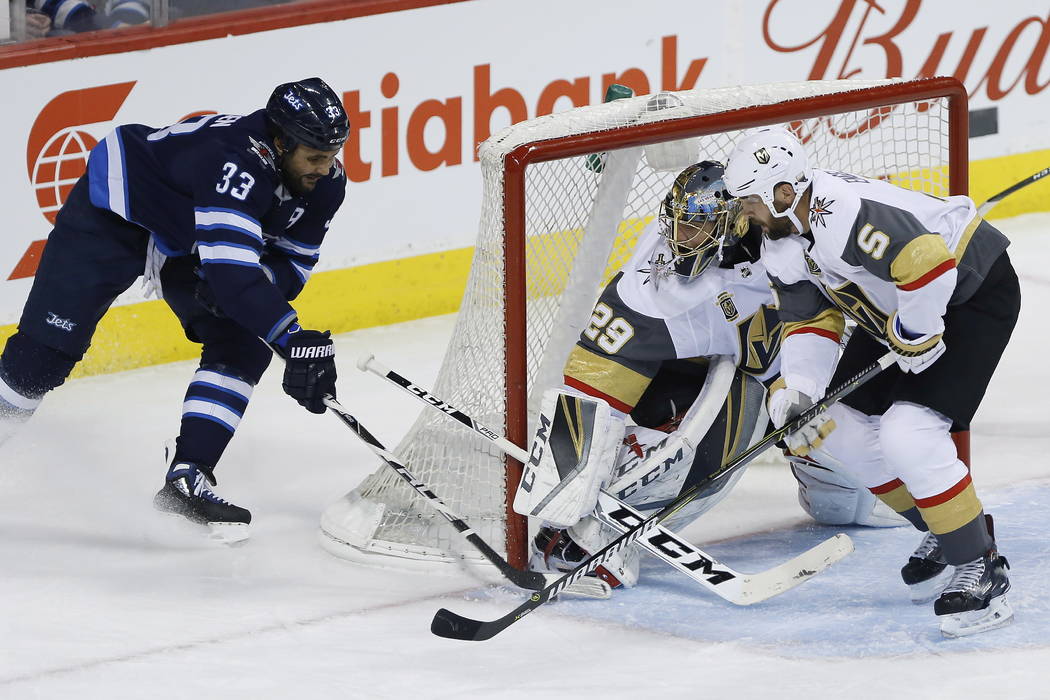 Winnipeg Jets' Dustin Byfuglien (33) attempts the wraparound on Vegas Golden Knights goaltender Marc-Andre Fleury (29) and Deryk Engelland (5) during the first period of an NHL hockey game Thursda ...