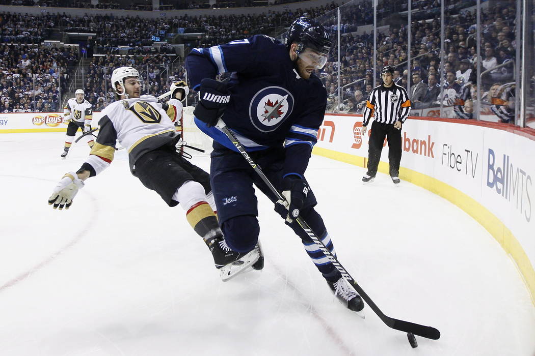 Vegas Golden Knights' Colin Miller (6) loses the fight for the puck against Winnipeg Jets' Adam Lowry (17) during the second period of an NHL hockey game Thursday, Feb. 1, 2018, in Winnipeg, Manit ...