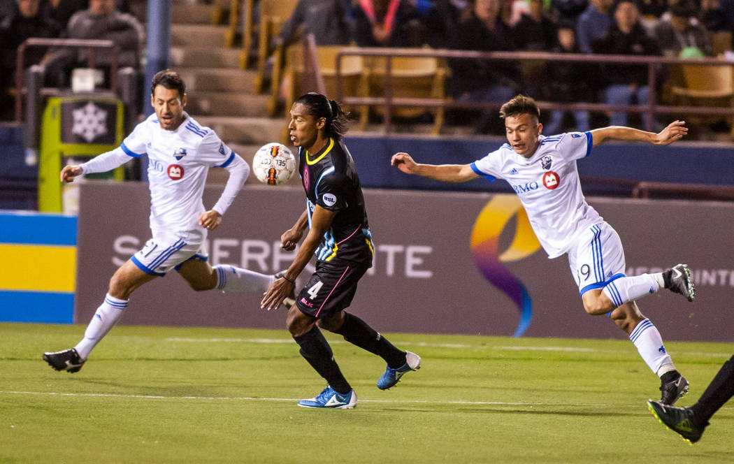 Las Vegas Lights' Joel Huiqui chests the ball while being chased by Montreal Impact players Matteo Mancosu, left, and Ken Krolicki, right, during the first Las Vegas Lights FC game at Cashman Fiel ...