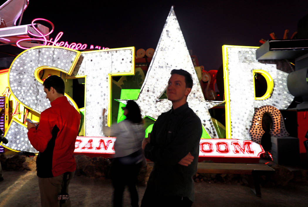 Attendees walk past signs that are illuminated in "Brilliant!"– an audiovisual immersion experience that uses technology advances to reanimate 40 monumental examples of th ...