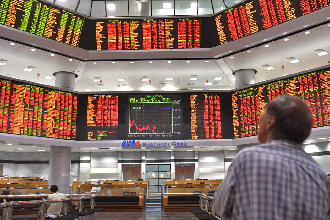 A Malaysian man watches trading boards at a private stock market gallery in Kuala Lumpur, Malaysia, Tuesday, Feb. 6, 2018. Asian markets were rattled Tuesday by the miseries on Wall Street, with J ...