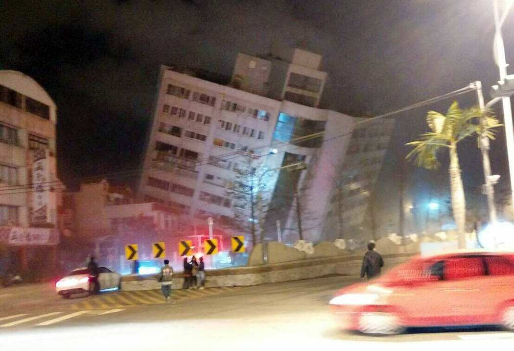 In this photo released by Hualien County Fire Bureau, rescuers are seen entering an building that collapsed onto its side from an early morning earthquake in Hualien County, eastern Taiwan, Wednes ...